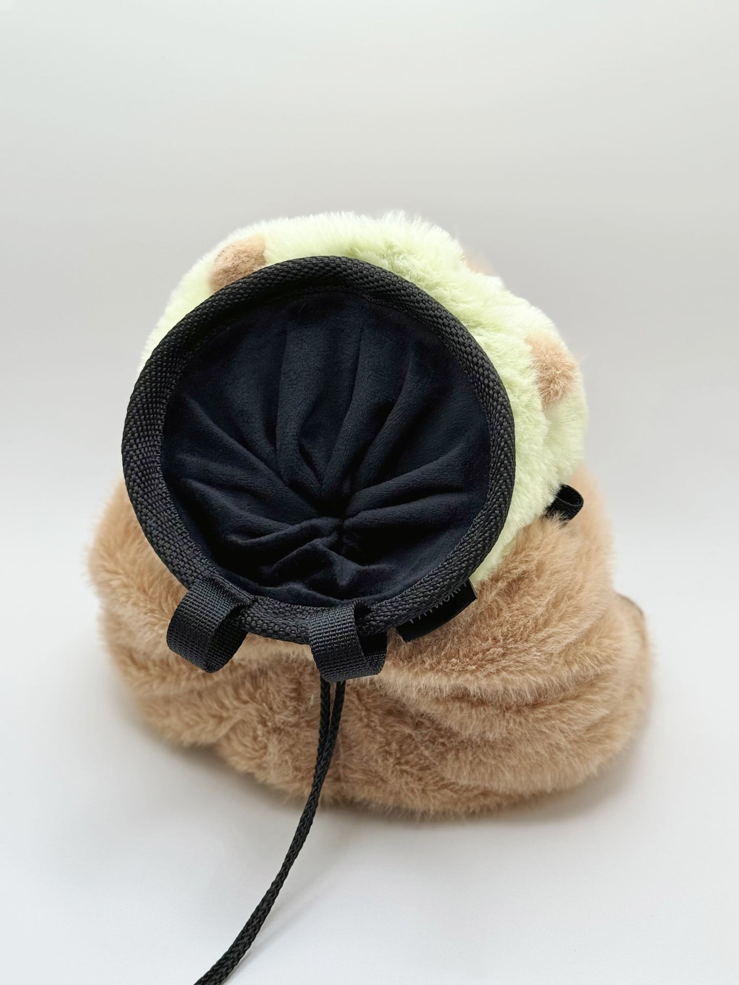 Handmade capybara-shaped climbing chalk bag dressed as a dinosaur, clutching a bubble tea cup