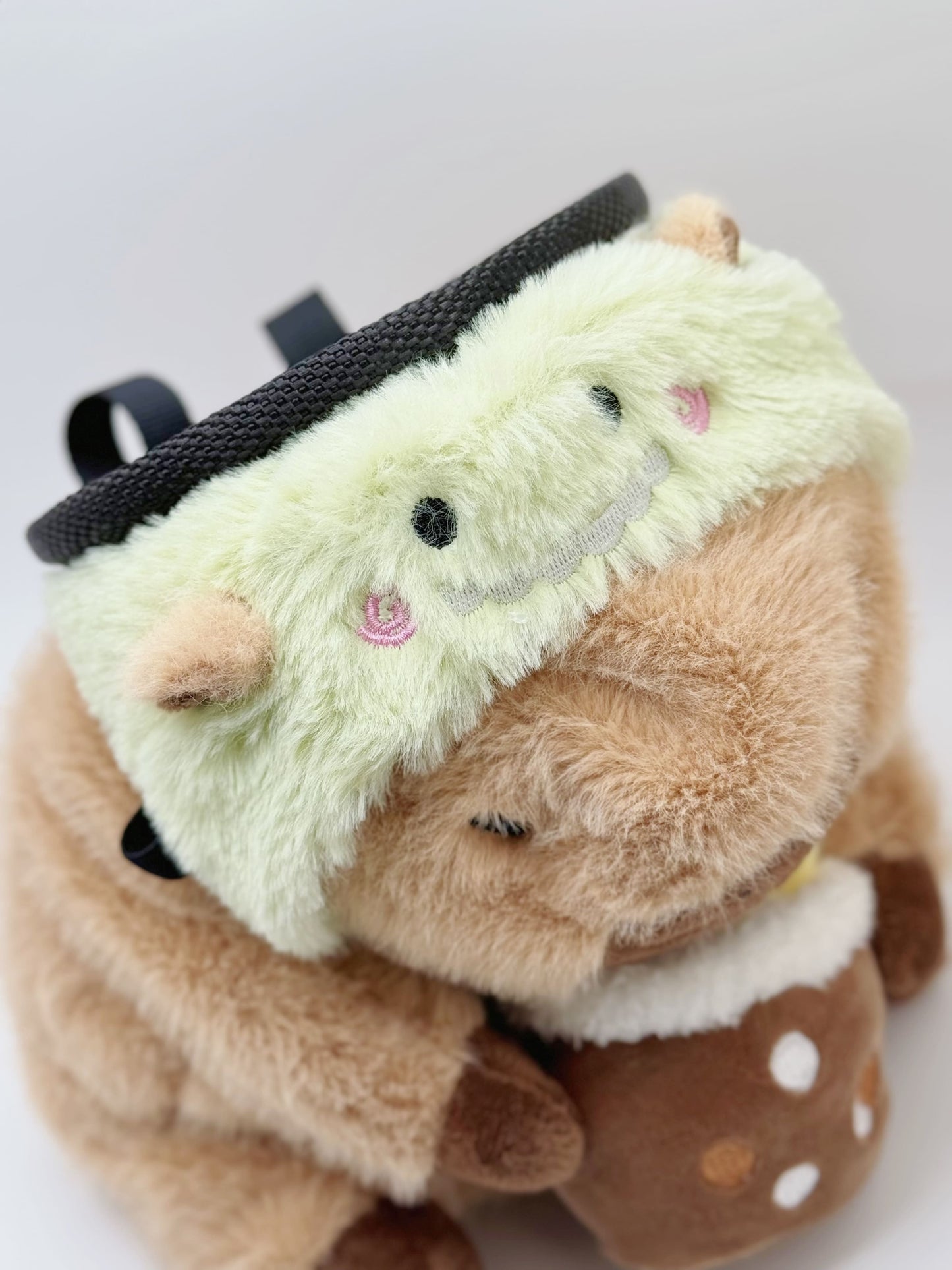 Handmade capybara-shaped climbing chalk bag dressed as a dinosaur, clutching a bubble tea cup