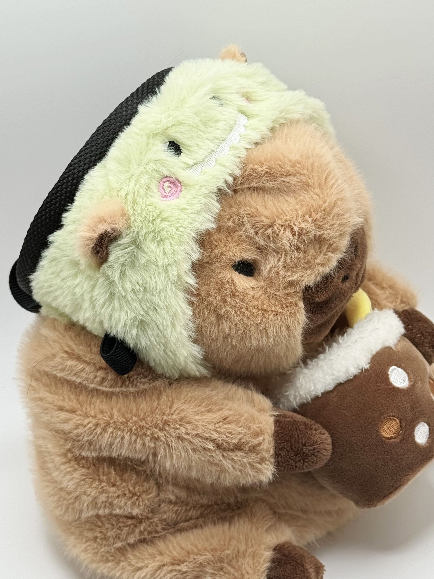 Handmade capybara-shaped climbing chalk bag dressed as a dinosaur, clutching a bubble tea cup