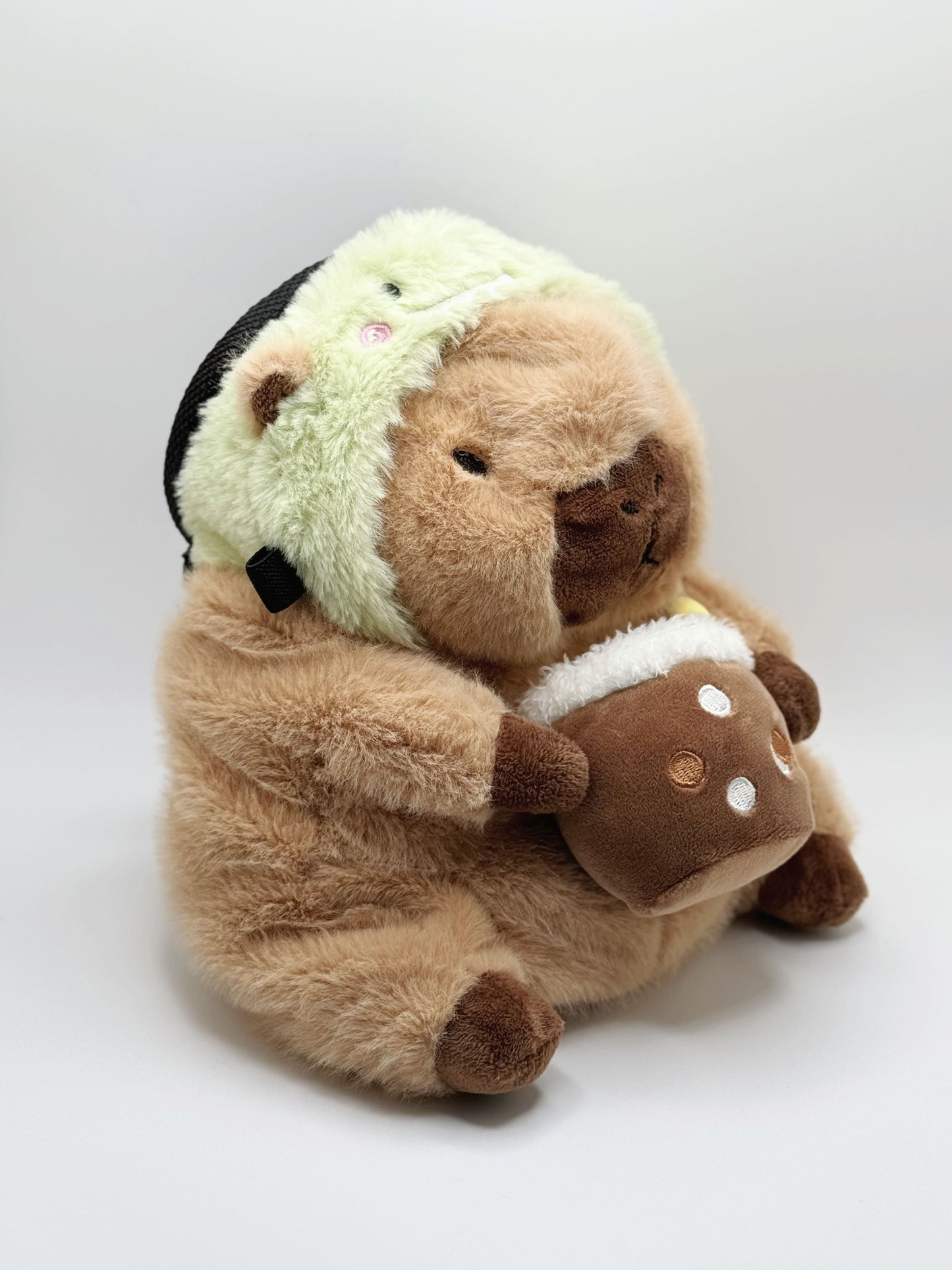 Handmade capybara-shaped climbing chalk bag dressed as a dinosaur, clutching a bubble tea cup