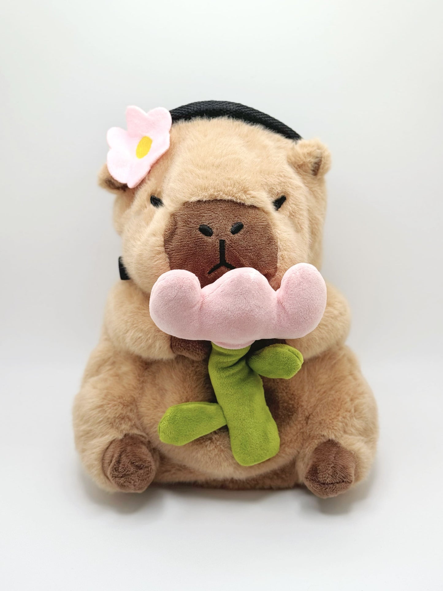 Handmade chalk bag featuring an adorable baby capybara holding a pink flower and wearing a cute dress-up outfit. Soft plush design, perfect for climbing and bouldering. Made by Fatworm