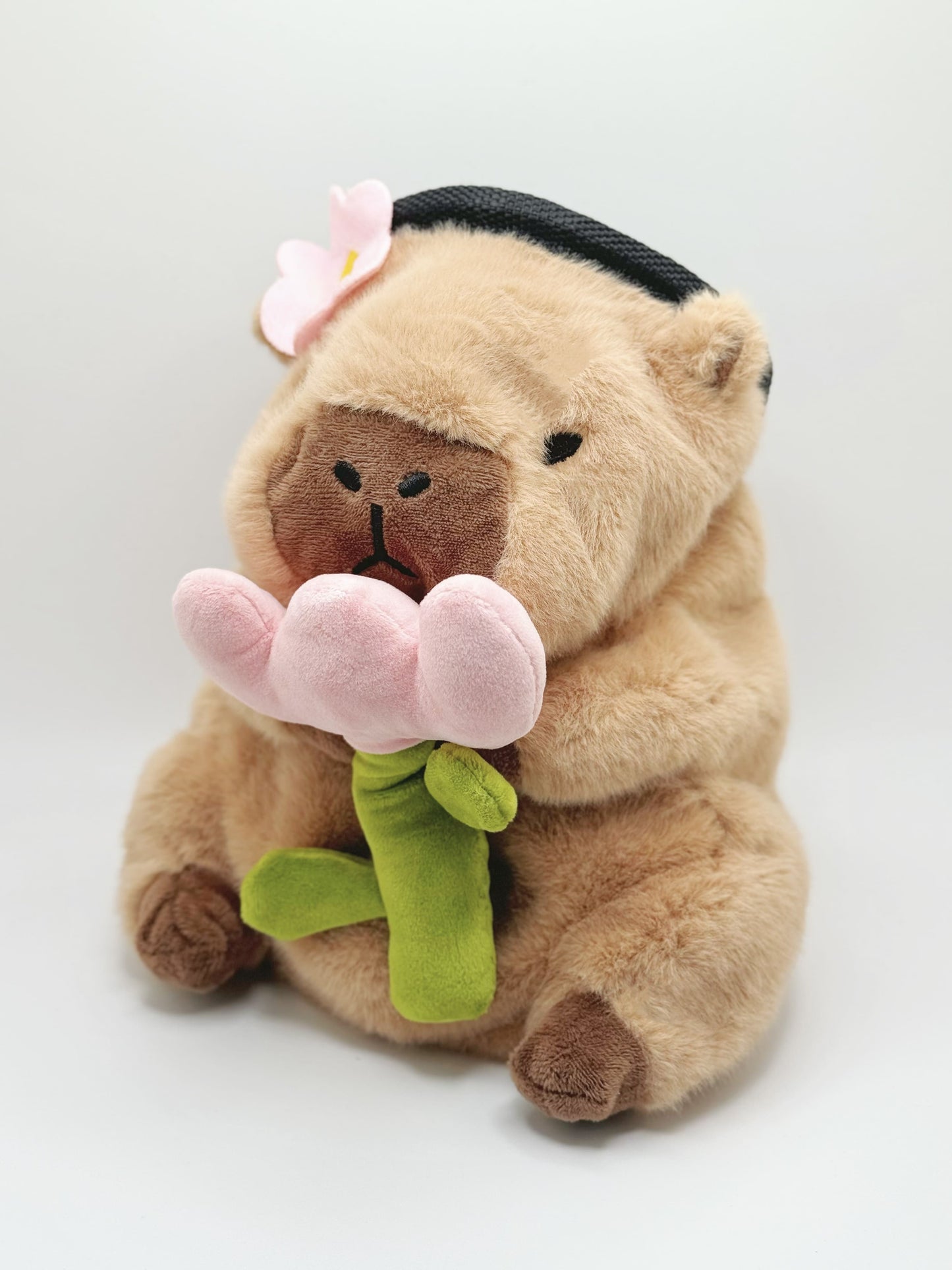 Handmade chalk bag featuring an adorable baby capybara holding a pink flower and wearing a cute dress-up outfit. Soft plush design, perfect for climbing and bouldering. Made by Fatworm