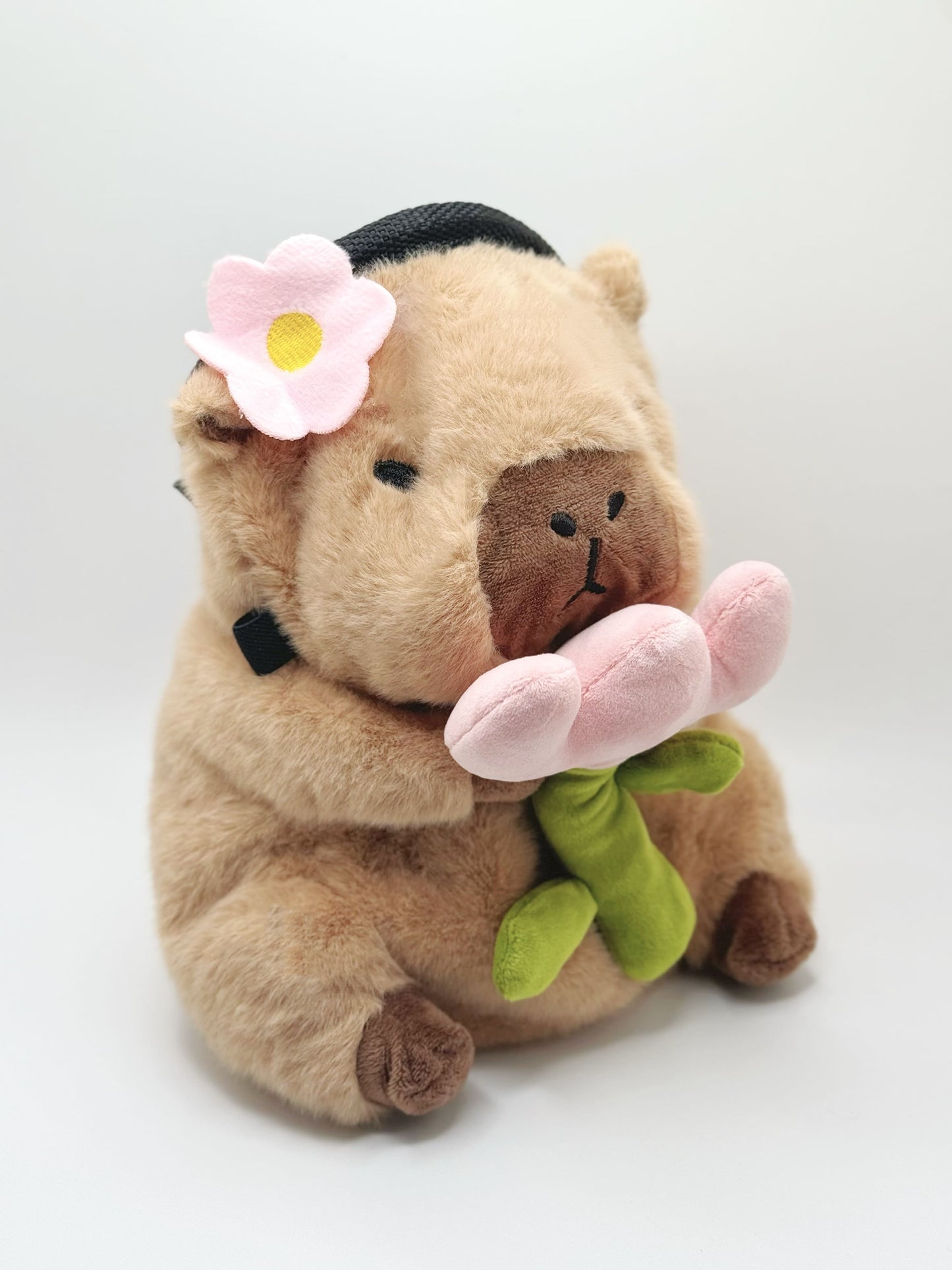 Handmade chalk bag featuring an adorable baby capybara holding a pink flower and wearing a cute dress-up outfit. Soft plush design, perfect for climbing and bouldering. Made by Fatworm