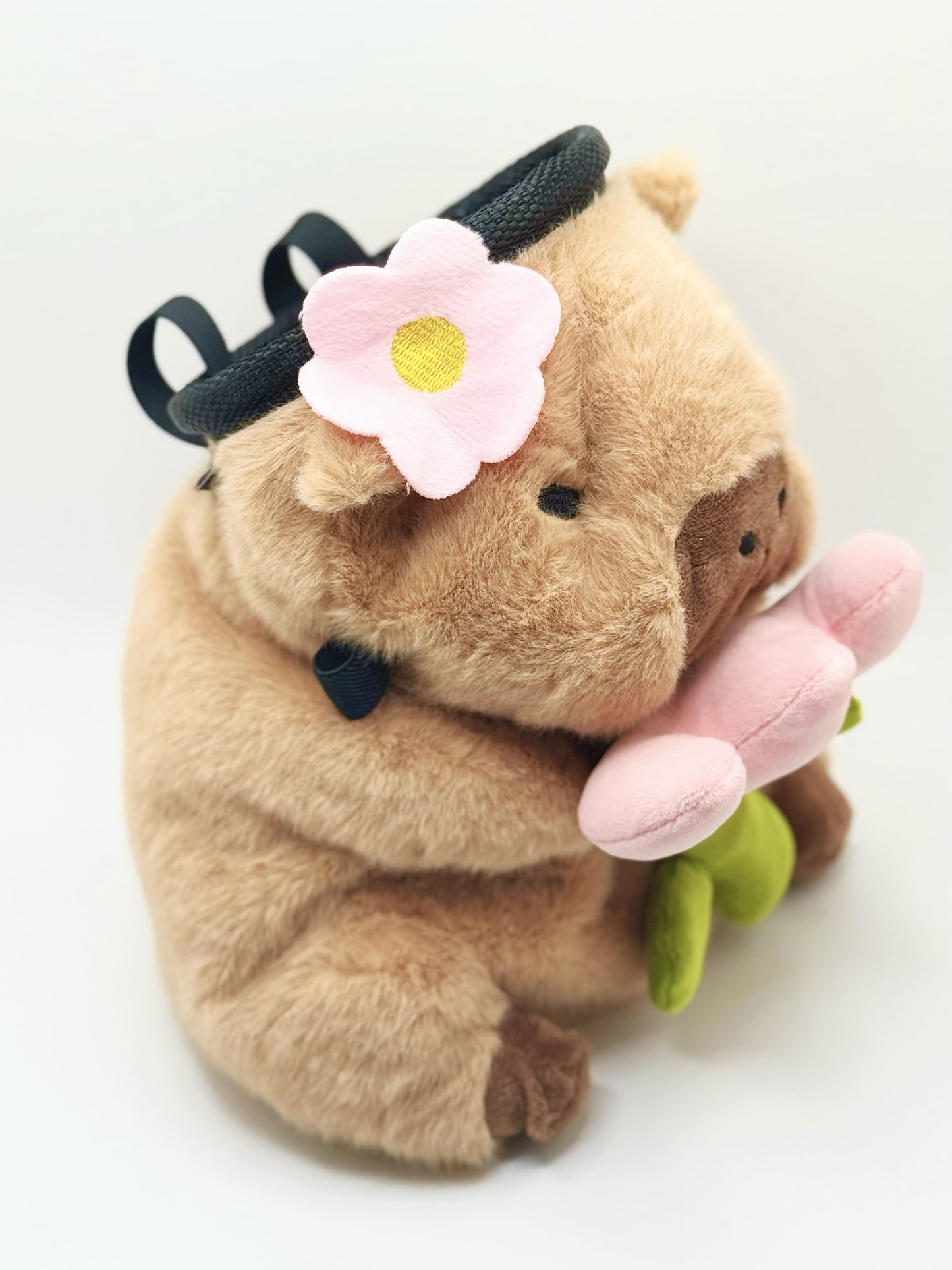 Handmade chalk bag featuring an adorable baby capybara holding a pink flower and wearing a cute dress-up outfit. Soft plush design, perfect for climbing and bouldering. Made by Fatworm