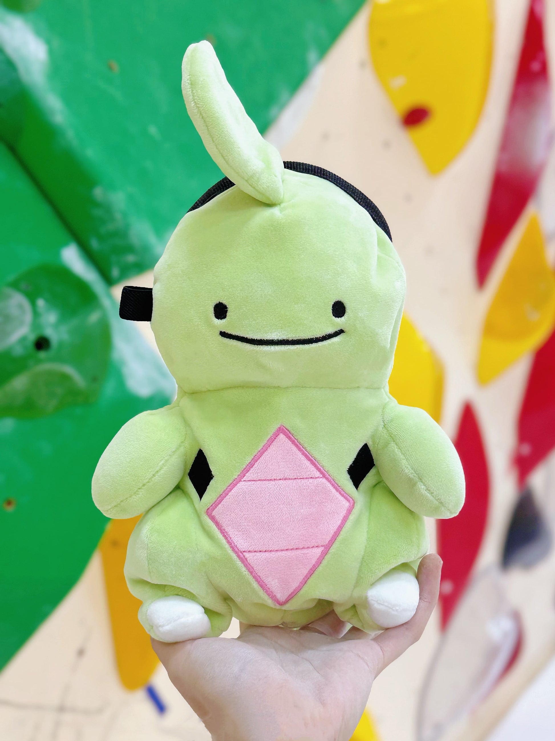 Handmade green and red plush Larvitar rock eater climbing chalk bag with a minimalist mimic face. Cute and unique climbing gift by Fatworm.