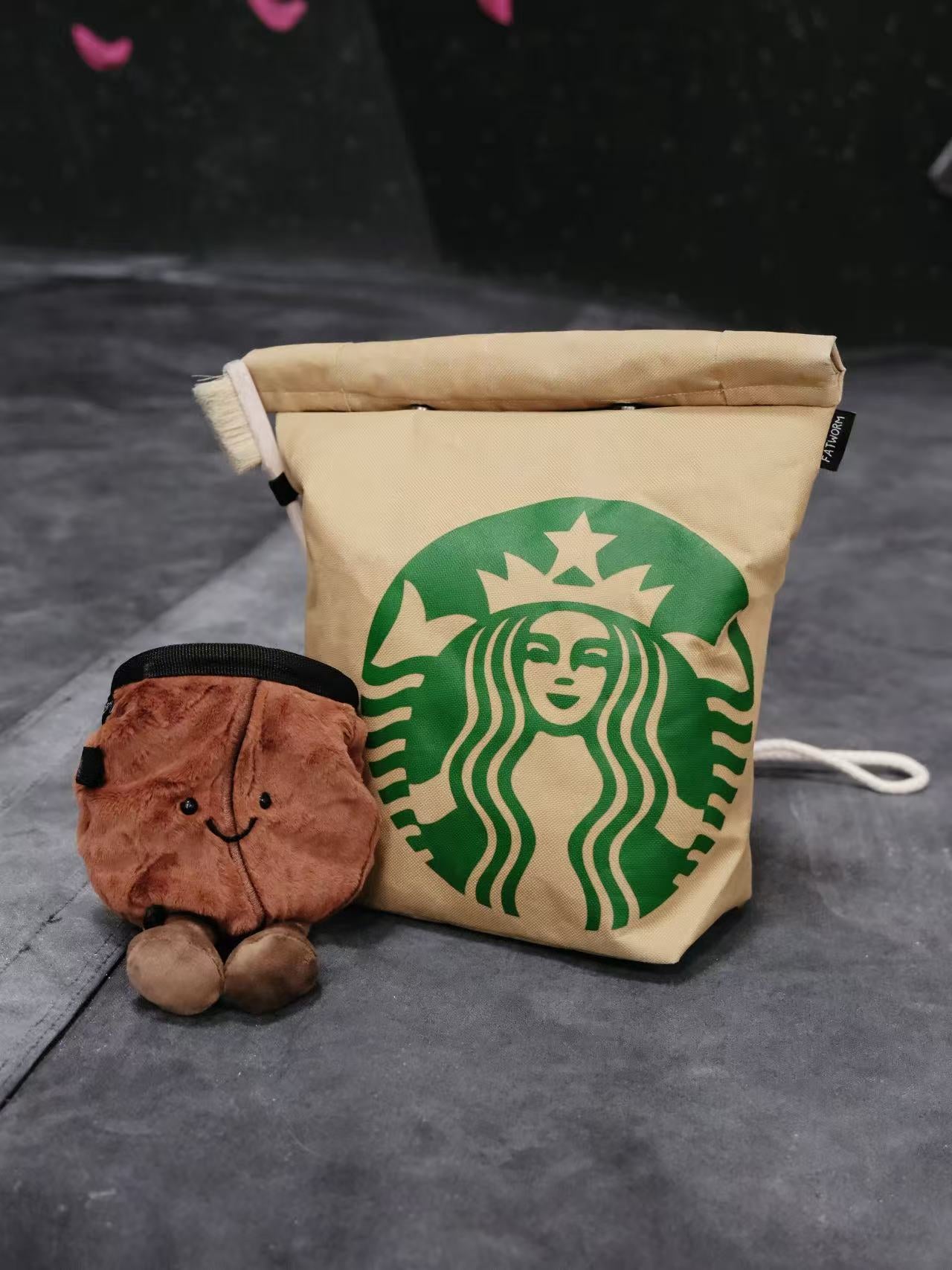 Functional and cute starbucks coffee-themed bouldering chalk bucket with a forest green exterior and black soft fleece lining, shown sitting upright on a climbing gym mat for scale.