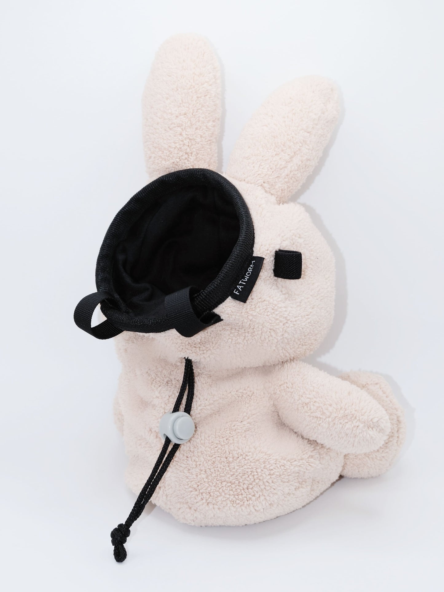 Handmade cream-colored Milk Tea Bunny plush climbing chalk bag with long floppy ears. Cute bouldering gift featuring a reinforced 12cm rim, secure drawstring, and deep black fleece lining. High-performance bouldering gear by Fatworm.
