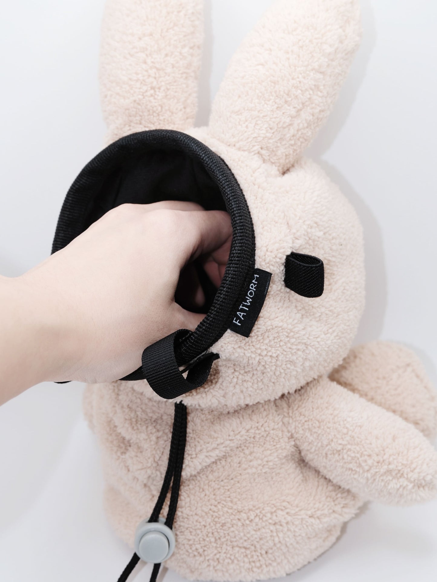 Handmade cream-colored Milk Tea Bunny plush climbing chalk bag with long floppy ears. Cute bouldering gift featuring a reinforced 12cm rim, secure drawstring, and deep black fleece lining. High-performance bouldering gear by Fatworm.