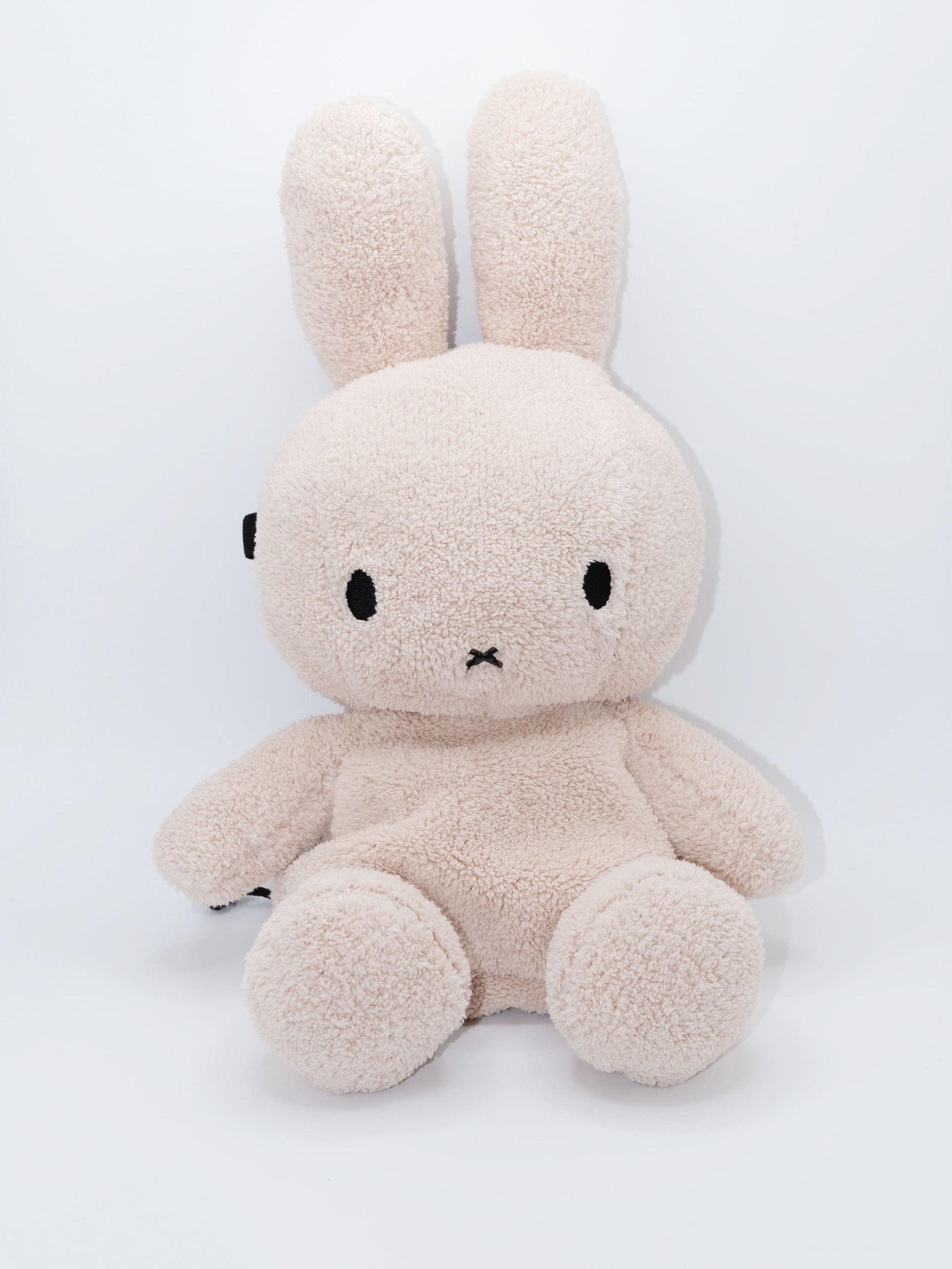 Handmade cream-colored Milk Tea Bunny plush climbing chalk bag with long floppy ears. Cute bouldering gift featuring a reinforced 12cm rim, secure drawstring, and deep black fleece lining. High-performance bouldering gear by Fatworm.