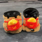 Handmade brown plush capybara climbing chalk bag wearing a red M backpack with removable plush fries. Unique bouldering gift featuring a reinforced 12cm rim and deep black fleece lining. Cute and funny bouldering gear by Fatworm.