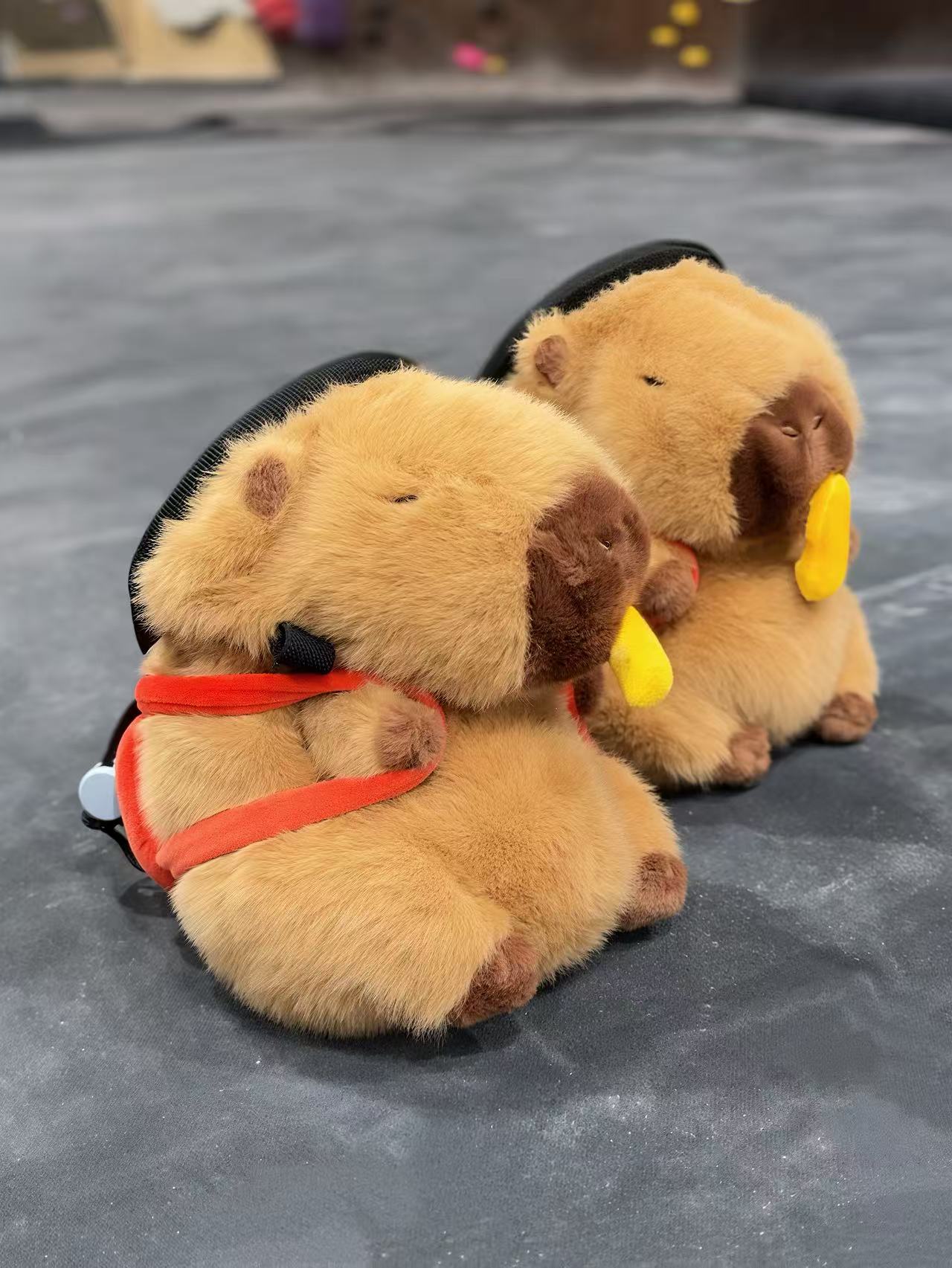 Handmade brown plush capybara climbing chalk bag wearing a red M backpack with removable plush fries. Unique bouldering gift featuring a reinforced 12cm rim and deep black fleece lining. Cute and funny bouldering gear by Fatworm.
