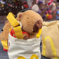 Handmade brown plush capybara climbing chalk bag wearing a red M backpack with removable plush fries. Unique bouldering gift featuring a reinforced 12cm rim and deep black fleece lining. Cute and funny bouldering gear by Fatworm.