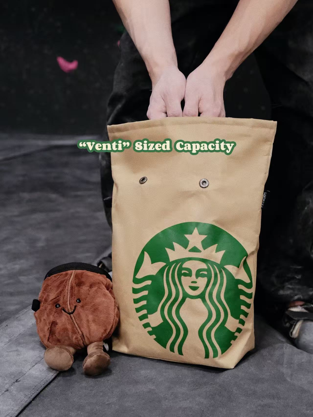 Functional and cute starbucks coffee-themed bouldering chalk bucket with a forest green exterior and black soft fleece lining, shown sitting upright on a climbing gym mat for scale.