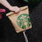 Functional and cute starbucks coffee-themed bouldering chalk bucket with a forest green exterior and black soft fleece lining, shown sitting upright on a climbing gym mat for scale.