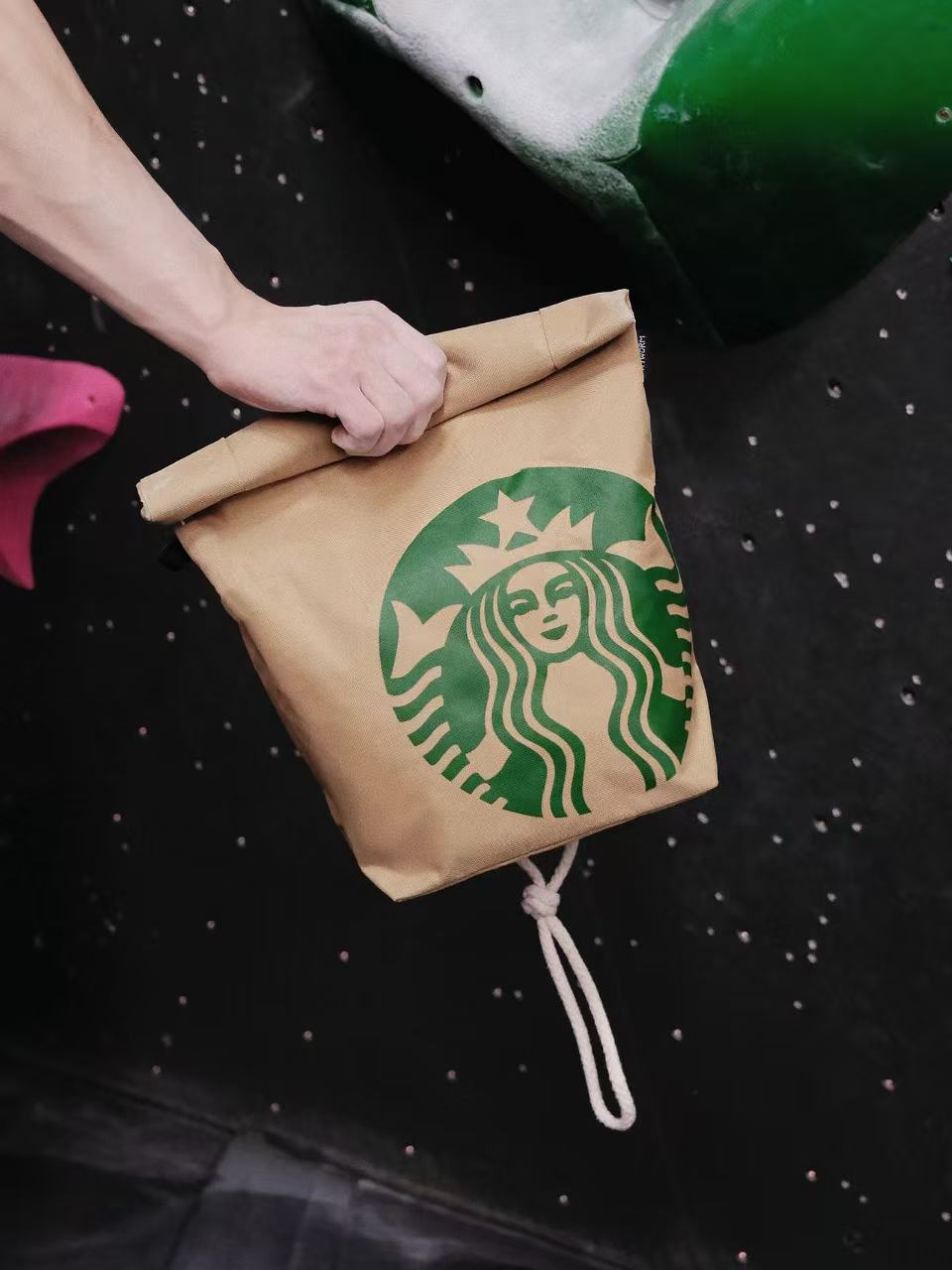 Functional and cute starbucks coffee-themed bouldering chalk bucket with a forest green exterior and black soft fleece lining, shown sitting upright on a climbing gym mat for scale.