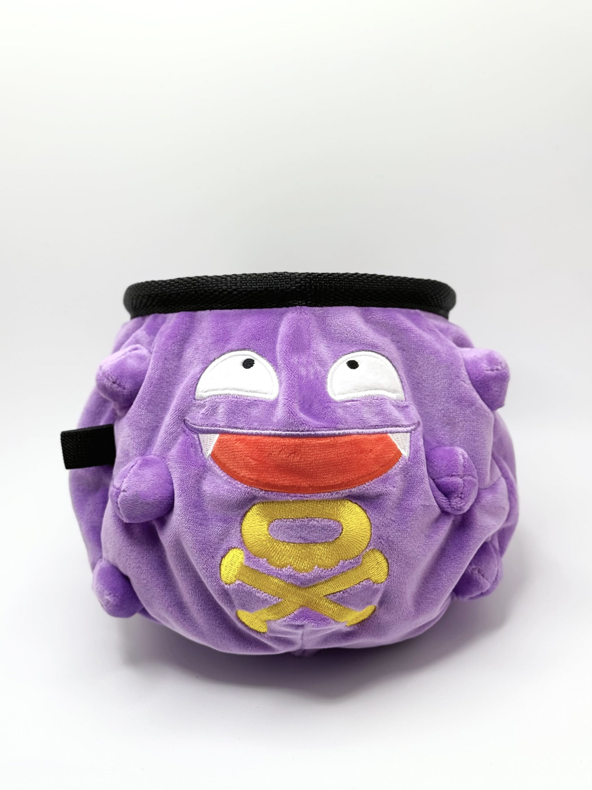 A cute anime plush chalk bag designed like Koffing by Fatworm. This functional purple bouldering and climbing accessory is handmade with a soft exterior, secure drawstring, and brush loop, making it perfect for rock climbing and a great gear addition for any climber.