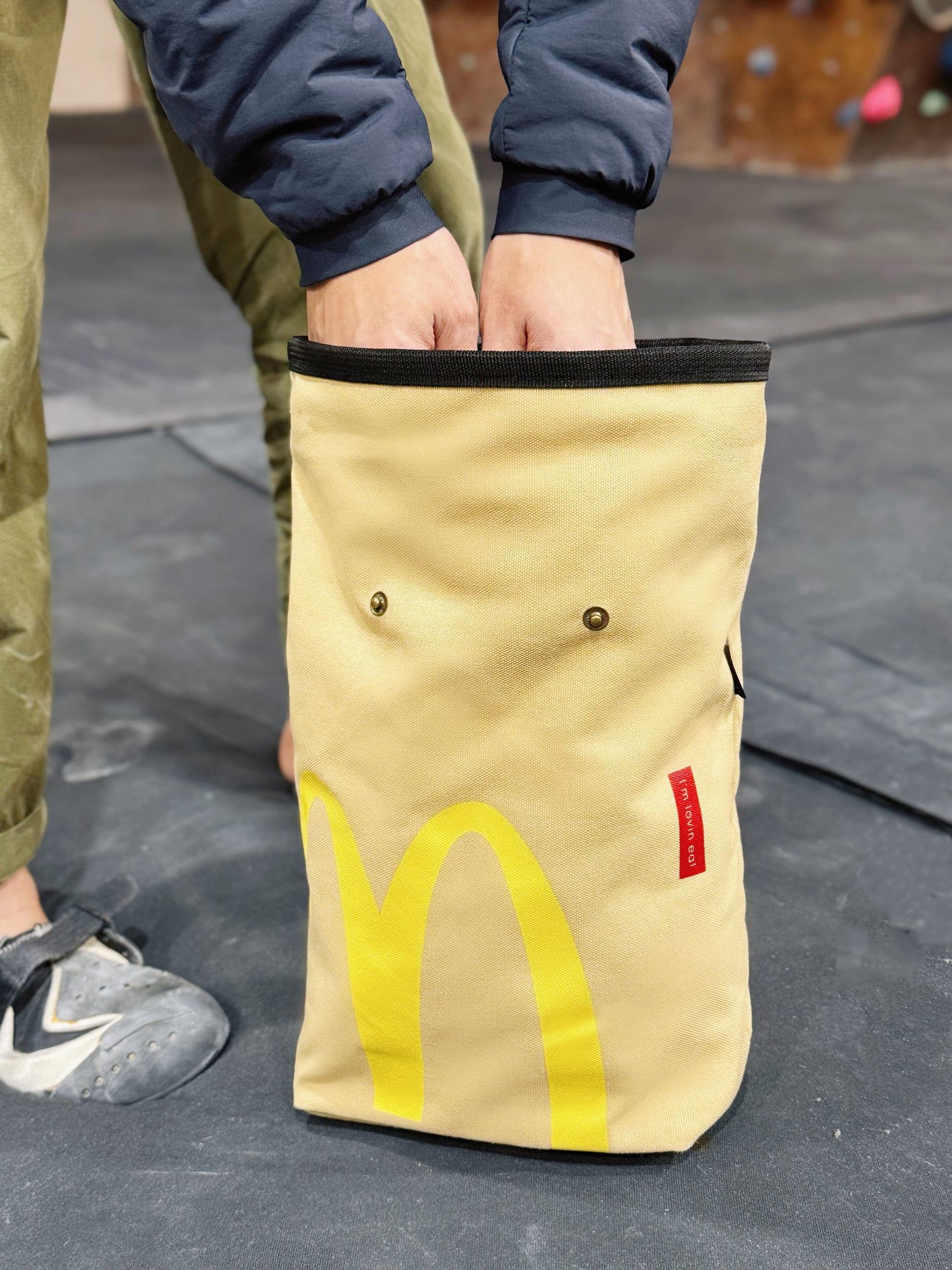 A cute plush bouldering chalk bucket by FATWORM featuring a classic red and yellow fast-food design. This functional and spacious ground-use accessory is handmade for bouldering and climbing for rock climbing, offering a long-durable design that makes the perfect climbing gift for a climber.