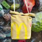 A cute plush bouldering chalk bucket by FATWORM featuring a classic red and yellow fast-food design. This functional and spacious ground-use accessory is handmade for bouldering and climbing for rock climbing, offering a long-durable design that makes the perfect climbing gift for a climber.