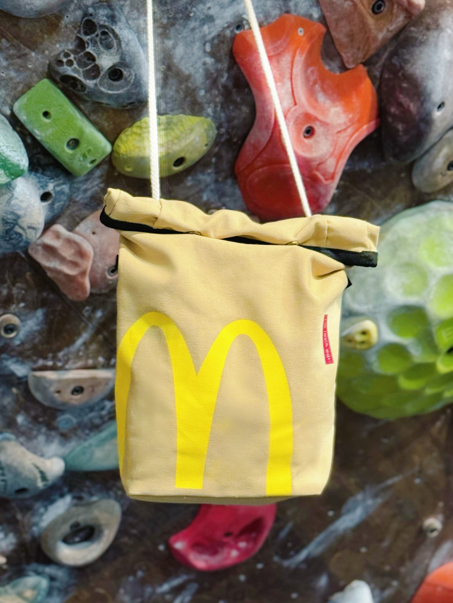 A cute plush bouldering chalk bucket by FATWORM featuring a classic red and yellow fast-food design. This functional and spacious ground-use accessory is handmade for bouldering and climbing for rock climbing, offering a long-durable design that makes the perfect climbing gift for a climber.