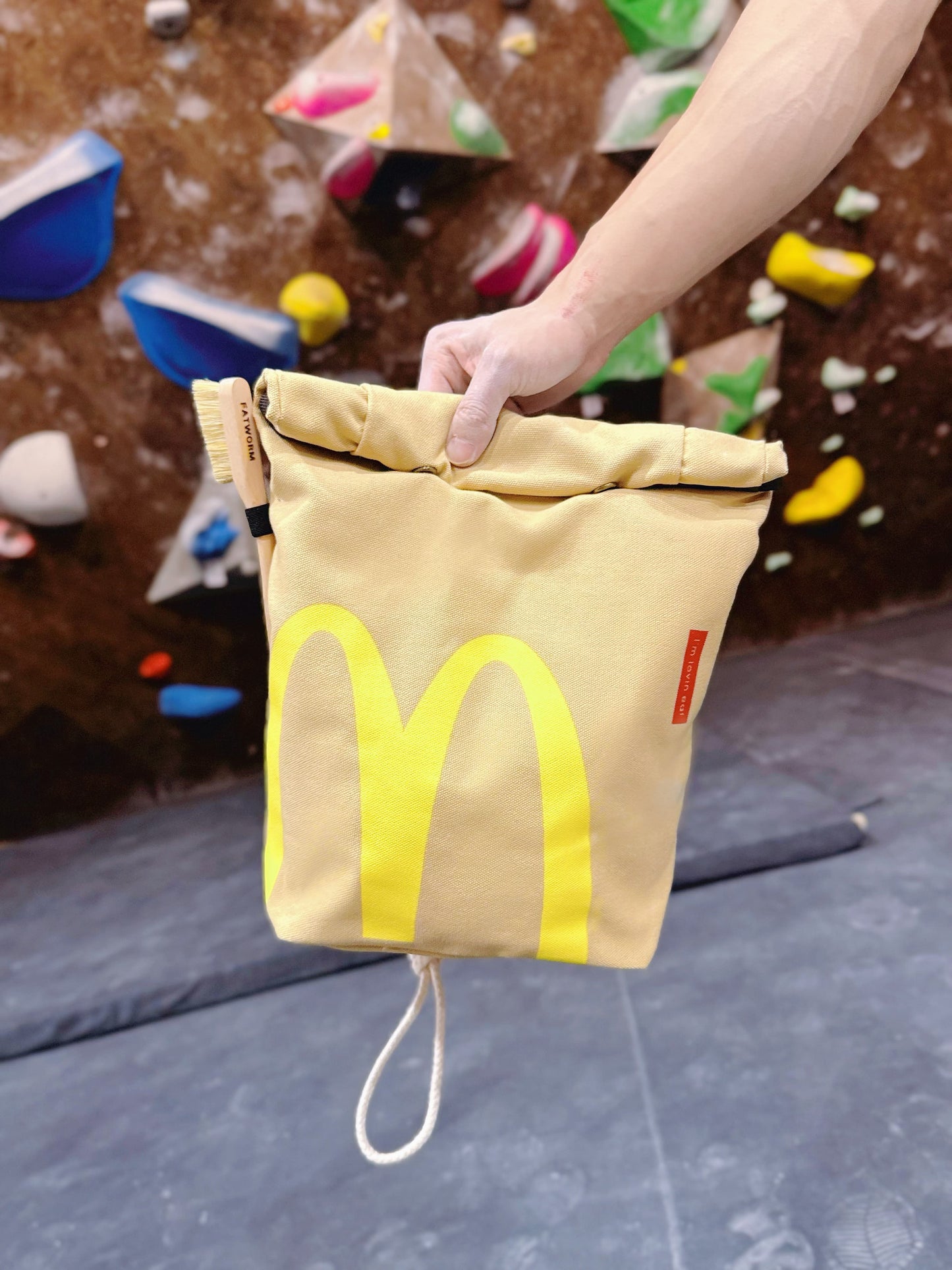A cute plush bouldering chalk bucket by FATWORM featuring a classic red and yellow fast-food design. This functional and spacious ground-use accessory is handmade for bouldering and climbing for rock climbing, offering a long-durable design that makes the perfect climbing gift for a climber.
