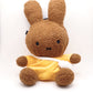 A cute anime plush chalk bag by FATWORM featuring a brown Mocha Bunny wearing a yellow dress. This functional and fluffy bouldering accessory is handmade for bouldering and climbing for rock climbing, offering a long-durable design that makes the perfect climbing gift for a climber.