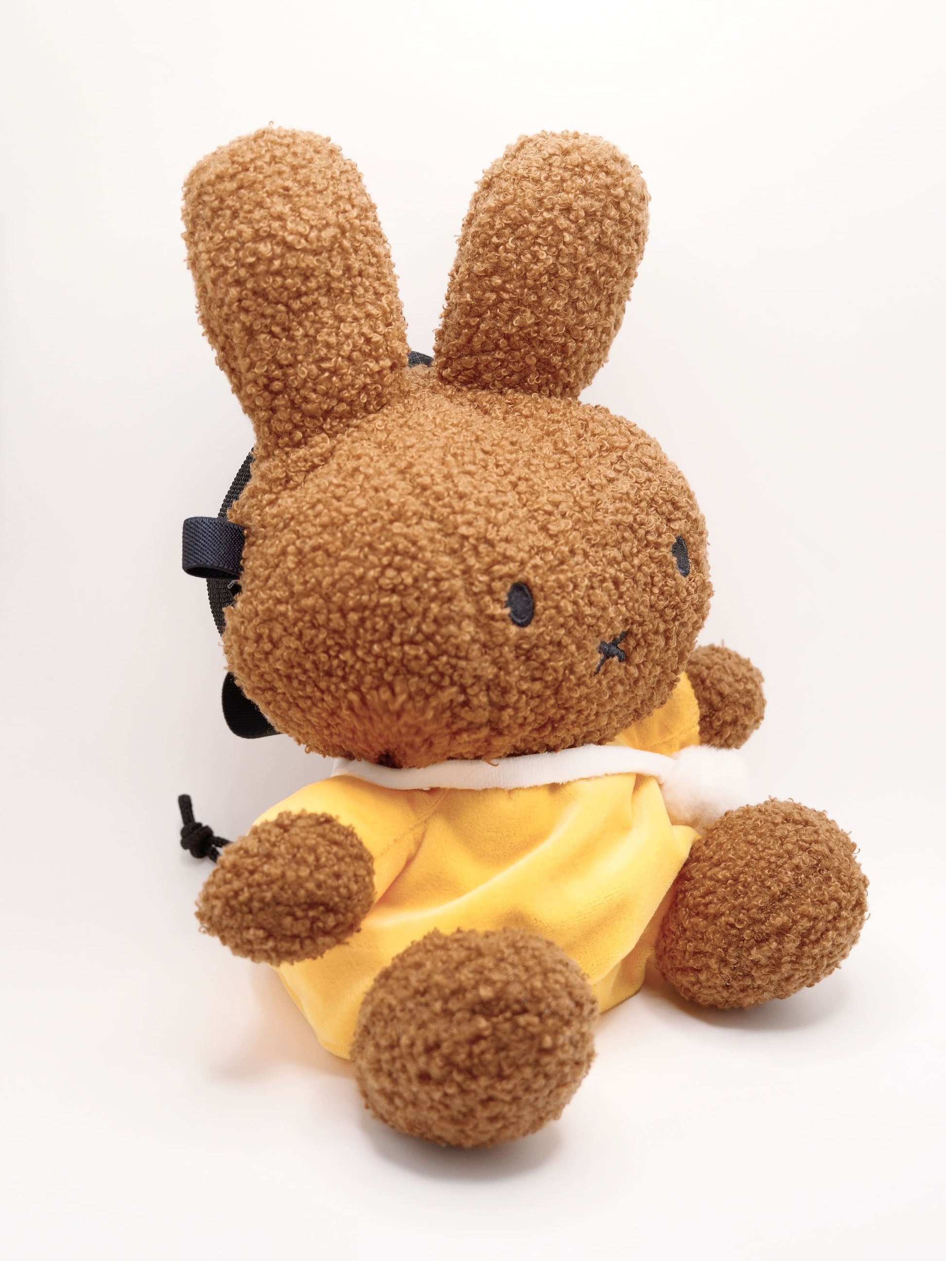 A cute anime plush chalk bag by FATWORM featuring a brown Mocha Bunny wearing a yellow dress. This functional and fluffy bouldering accessory is handmade for bouldering and climbing for rock climbing, offering a long-durable design that makes the perfect climbing gift for a climber.