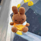 A cute anime plush chalk bag by FATWORM featuring a brown Mocha Bunny wearing a yellow dress. This functional and fluffy bouldering accessory is handmade for bouldering and climbing for rock climbing, offering a long-durable design that makes the perfect climbing gift for a climber.