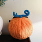 A cute anime plush chalk bag by FATWORM featuring an orange magical fire fruit with swirling flame patterns and a green stem, inspired by the fiery hero Ace. This functional and fluffy bouldering accessory is handmade for bouldering and climbing for rock climbing, offering a long-durable design that makes the perfect climbing gift for a climber.