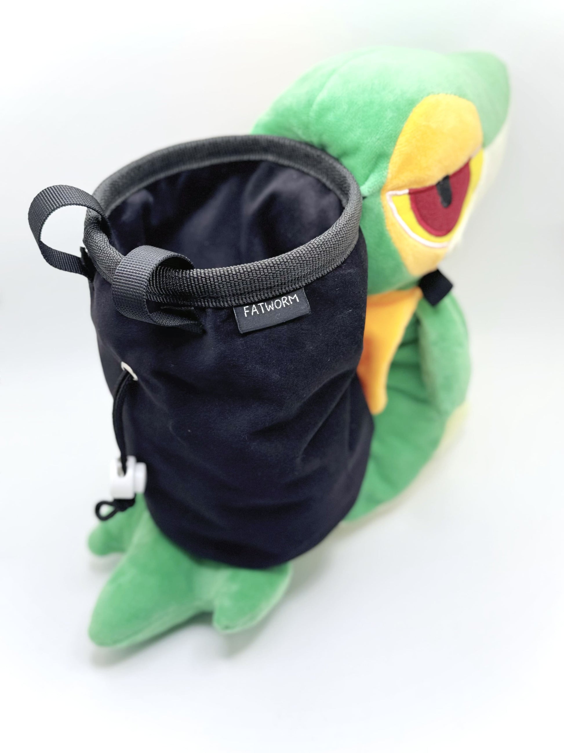 A cute, handmade plush climbing chalk bag designed to look like the Snivy, featuring a sleek green and cream body with yellow leaf-like accents and large, confident eyes. Designed with high functionality by a climber, it includes a wide black rim opening at the top for easy chalk access. A great climbing gift for trainers who want to catch them all.