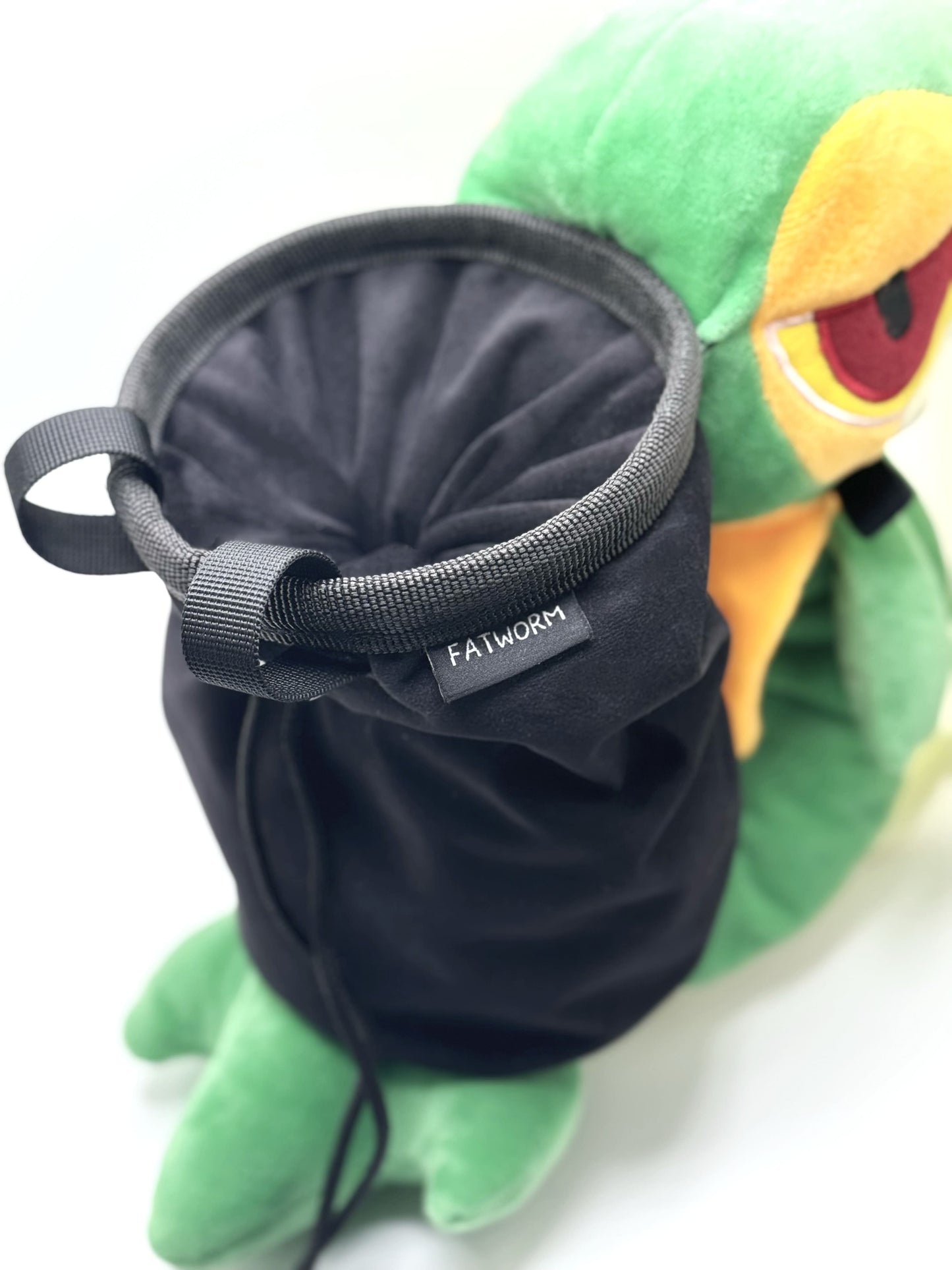 A cute, handmade plush climbing chalk bag designed to look like the Snivy, featuring a sleek green and cream body with yellow leaf-like accents and large, confident eyes. Designed with high functionality by a climber, it includes a wide black rim opening at the top for easy chalk access. A great climbing gift for trainers who want to catch them all.
