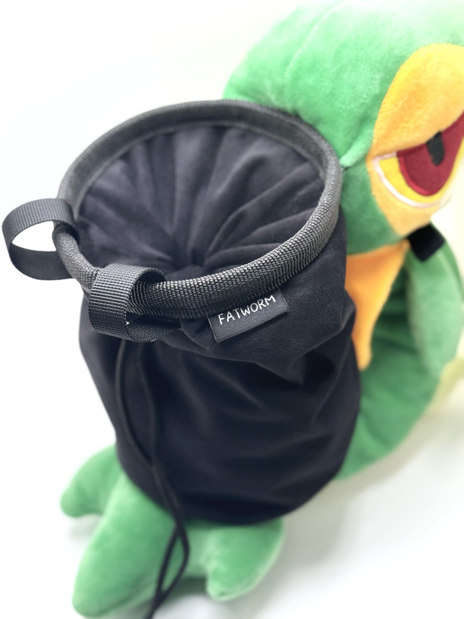 A cute, handmade plush climbing chalk bag designed to look like the Snivy, featuring a sleek green and cream body with yellow leaf-like accents and large, confident eyes. Designed with high functionality by a climber, it includes a wide black rim opening at the top for easy chalk access. A great climbing gift for trainers who want to catch them all.