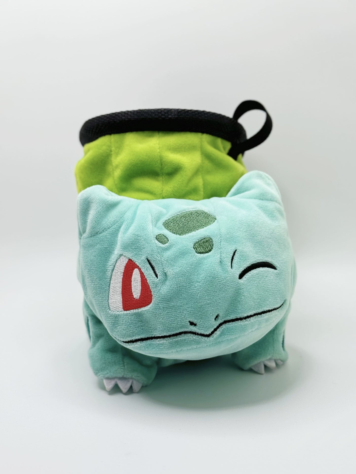 Winking Bulbasaur cute plush chalk bag with one eye closed and a cheeky smile. High-quality, functional climbing gear with a compact chalk-saver design.