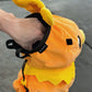 Handmade orange plush Torchic fire chick climbing chalk bag for bouldering. Features yellow feather tufts and a cute bird silhouette. High-quality plush bouldering gift with a 12cm reinforced rim, secure drawstring, and deep black fleece lining for rock climbing.